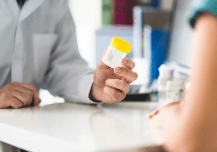 A doctor holds a pill bottle in front of a patient