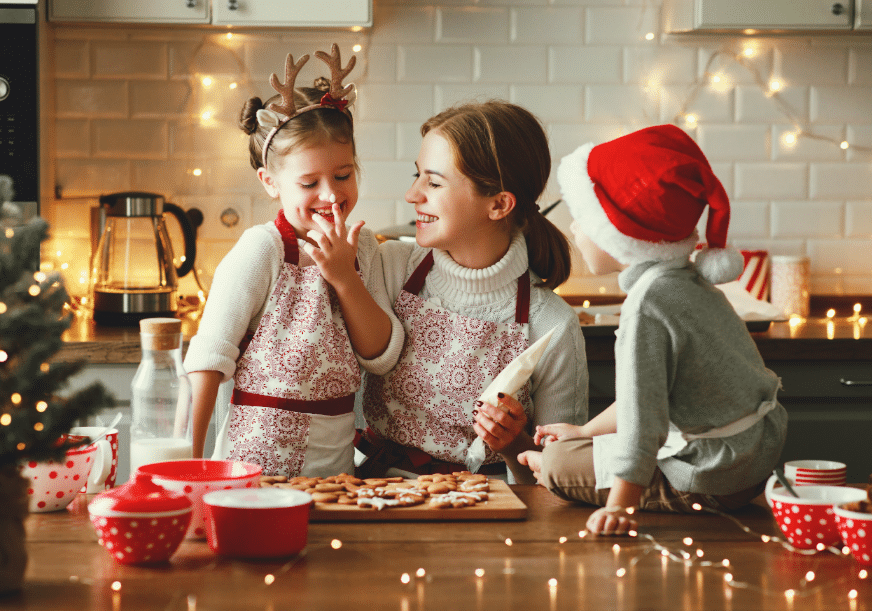 a woman makes christmas cookies with her two children