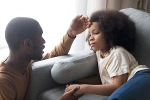 a parent holds their hand against a sick child's forehead