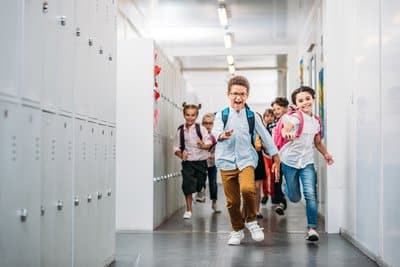 A group of children run through a school hallway