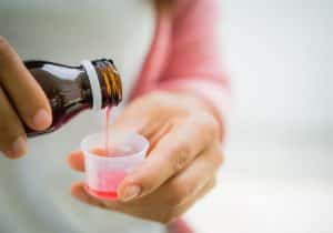 a person pours medicine into a small cup