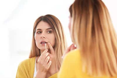 A woman inspects her lip for cold sores