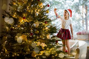 a girl decorates a christmas tree