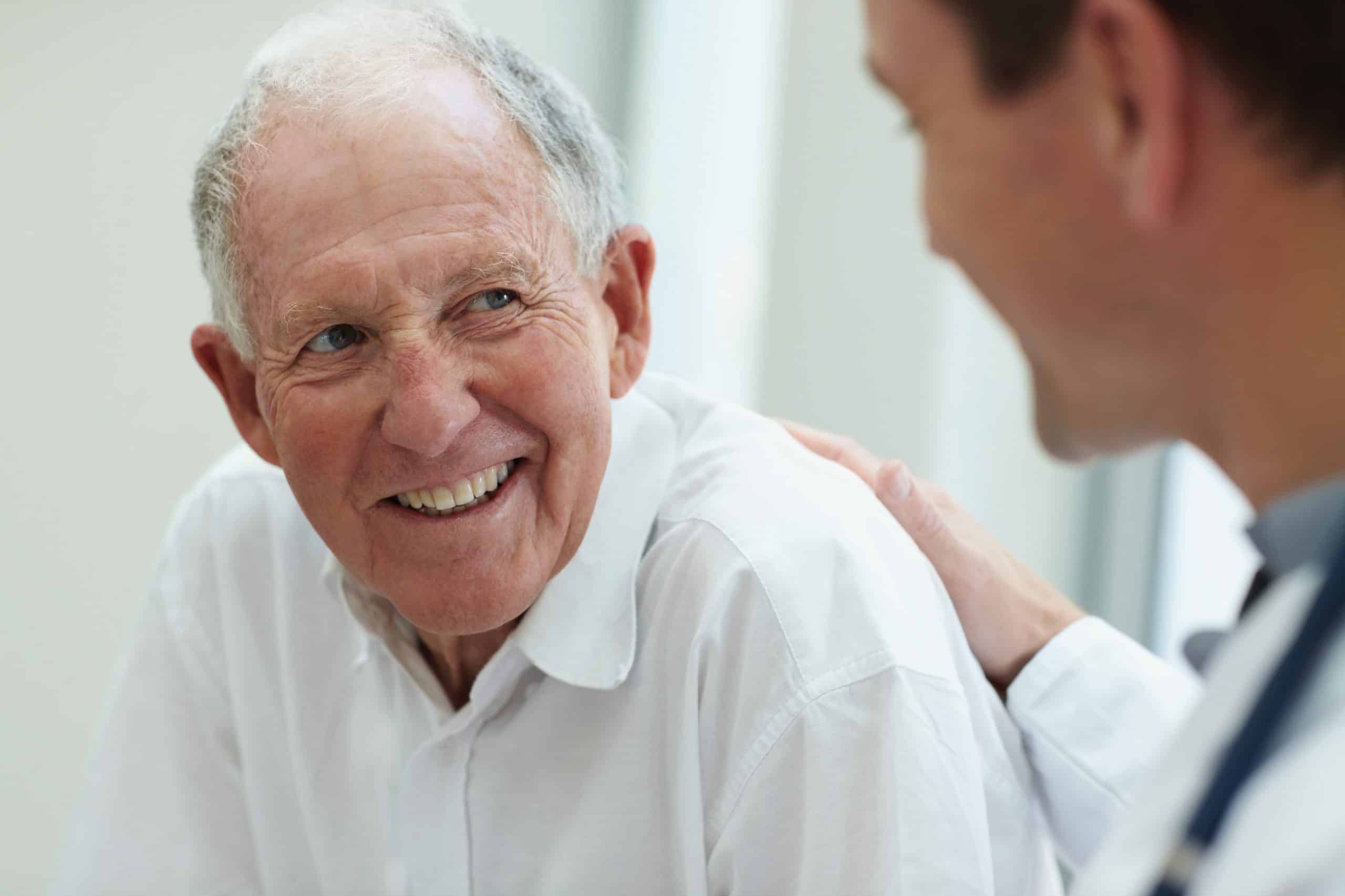 a doctor pats an old man on the back