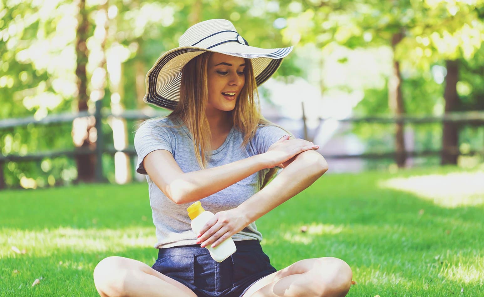 A girl applies sunscreen to her arm