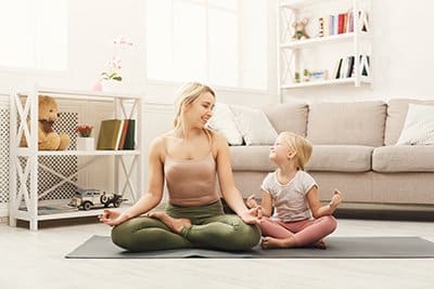 A woman does yoga with her daughter