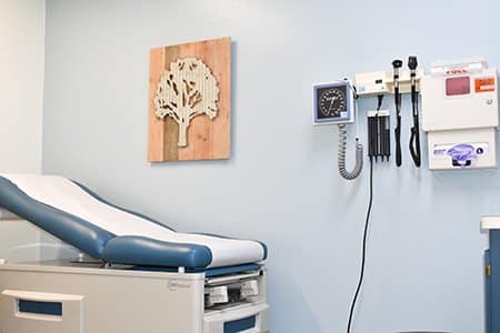 An empty doctor's office with a patient's chair and some medical tools