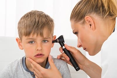 A doctor inspects a boy's ear