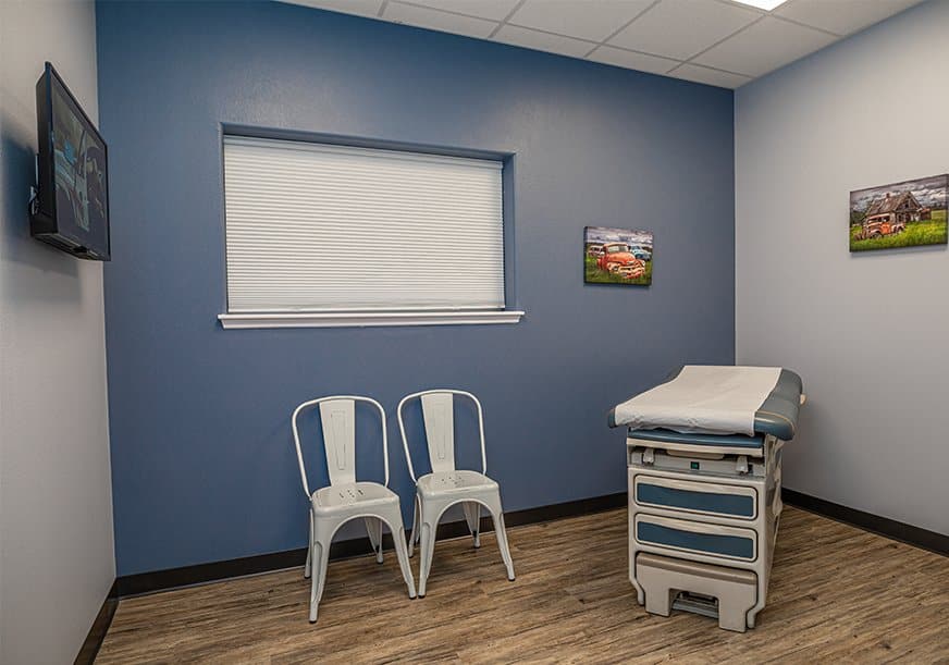 An empty doctor's office with chairs and an examination table