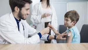 A doctor gives a boy a shot