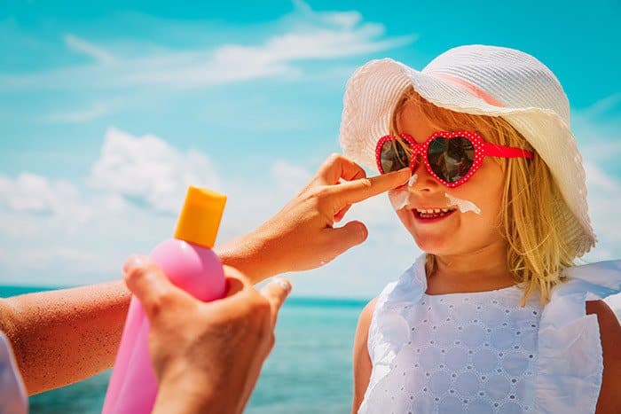 a woman puts sunscreen on her child's face