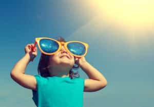 a child wears giant sunglasses on a sunny day