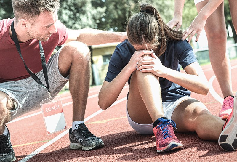 an injured runner clutches her knees