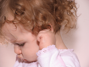 a baby clutches her ear in pain