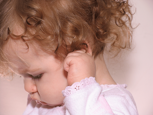 a baby clutches her ear in pain