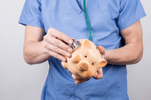 a doctor holds a stethoscope to a piggy bank