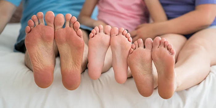 Three barefoot people, mother, father and daughter resting on the sofa
