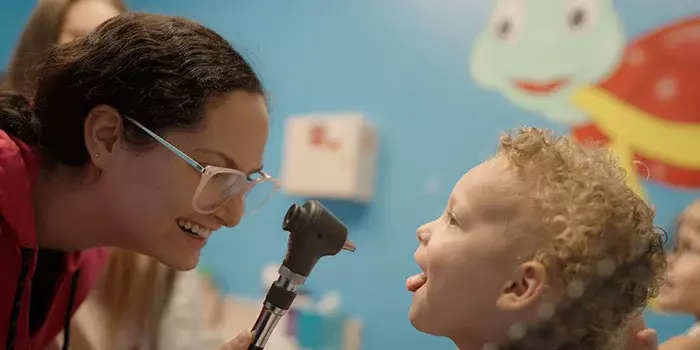 Doctor checking child's mouth with otoscope, how long does strep throat last?
